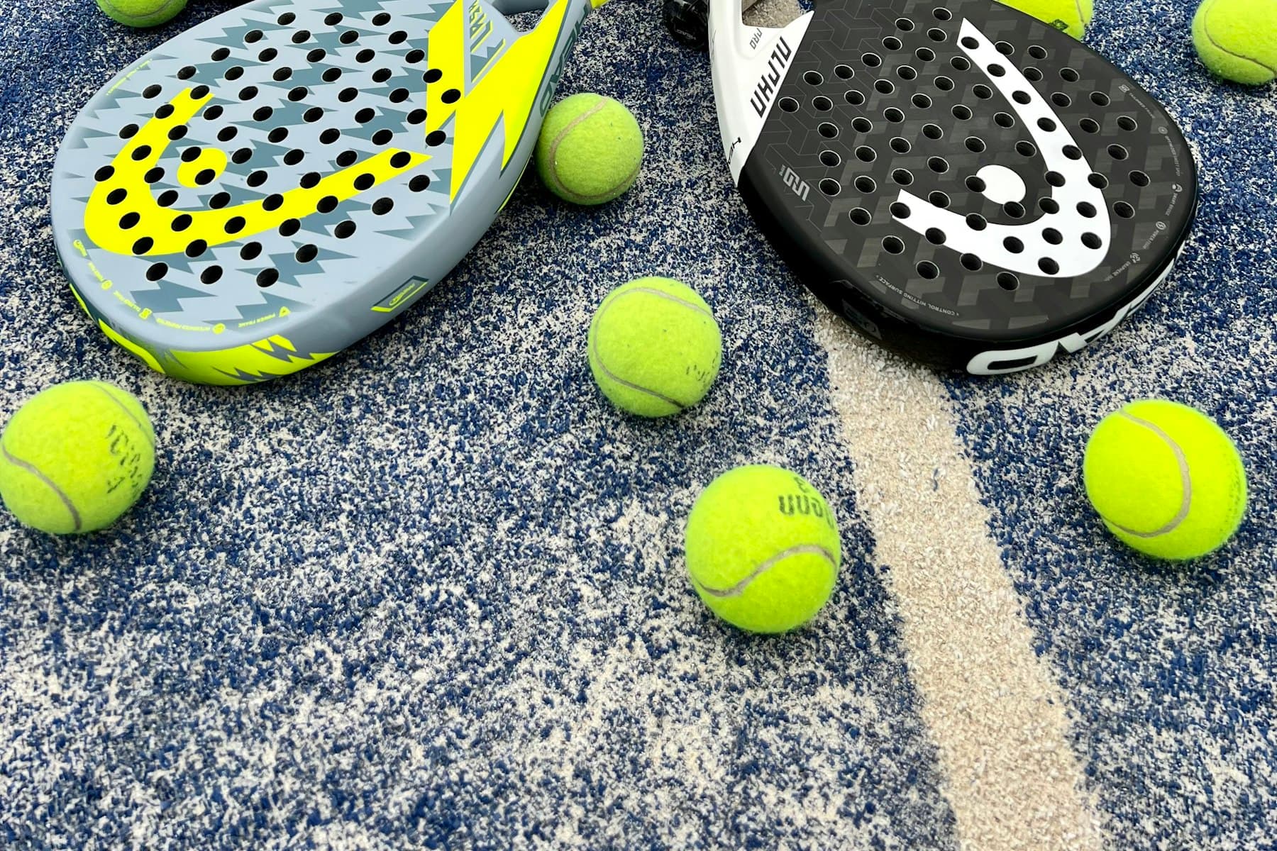 Padel rackets and balls on a vivid blue padel court