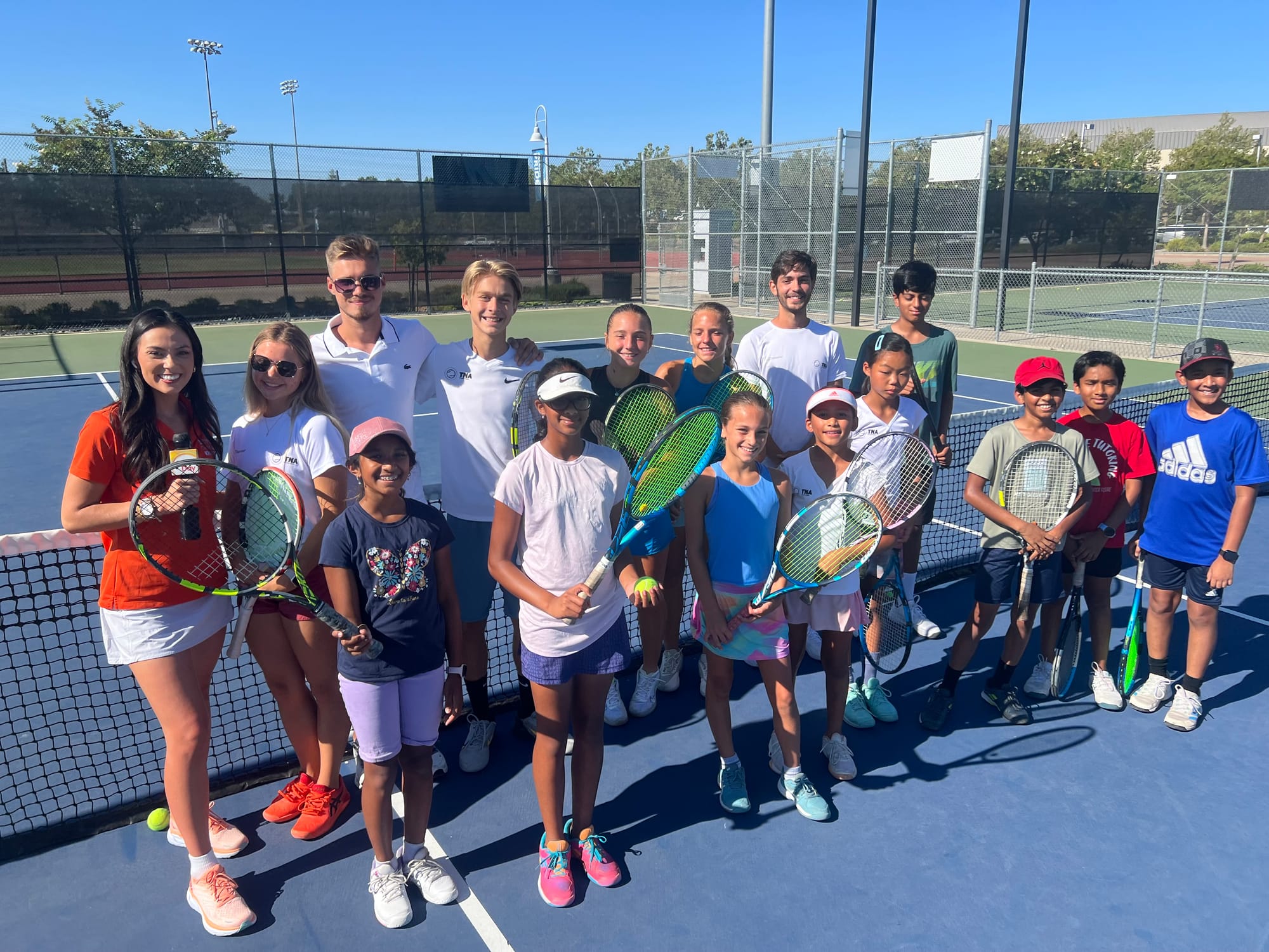 TNA Pro Academy players and coaches with their rackets at the net in California