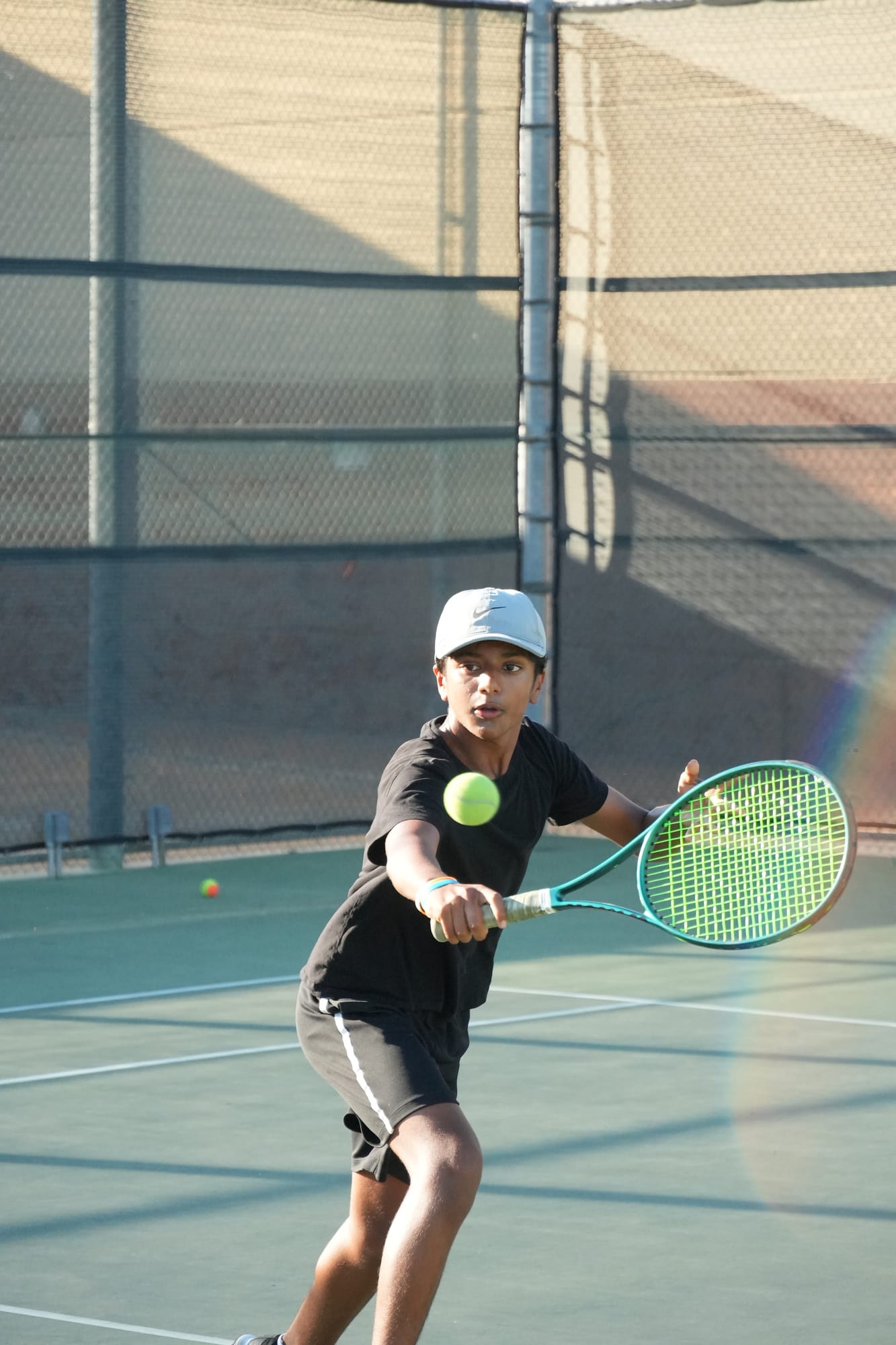 A competitive junior player hitting a backhand volley at the net