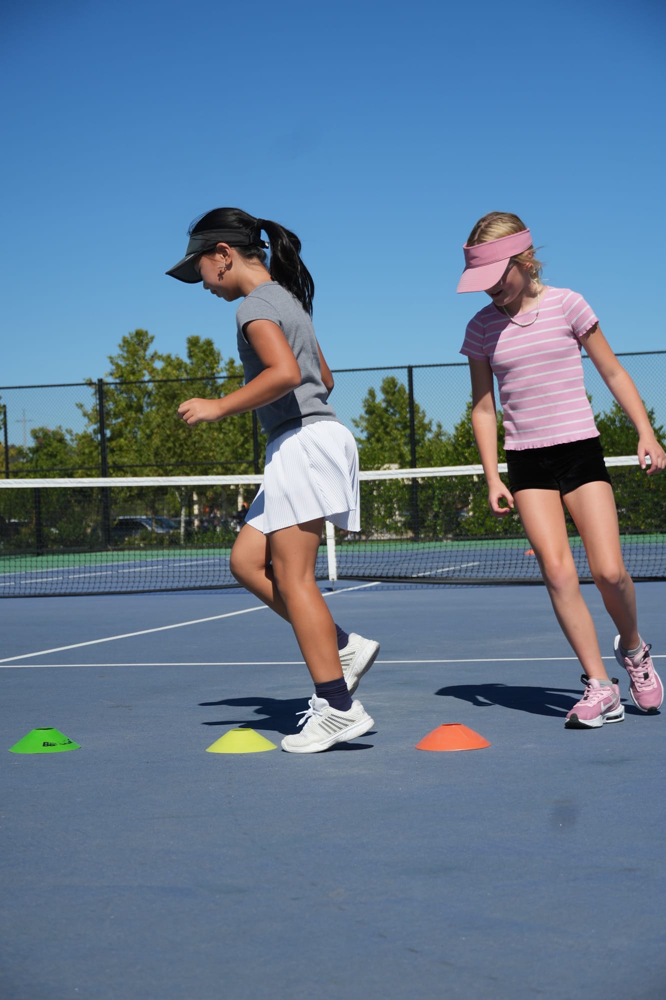 Two junior players doing cone footwork drills on a TNA Pro Academy tennis court