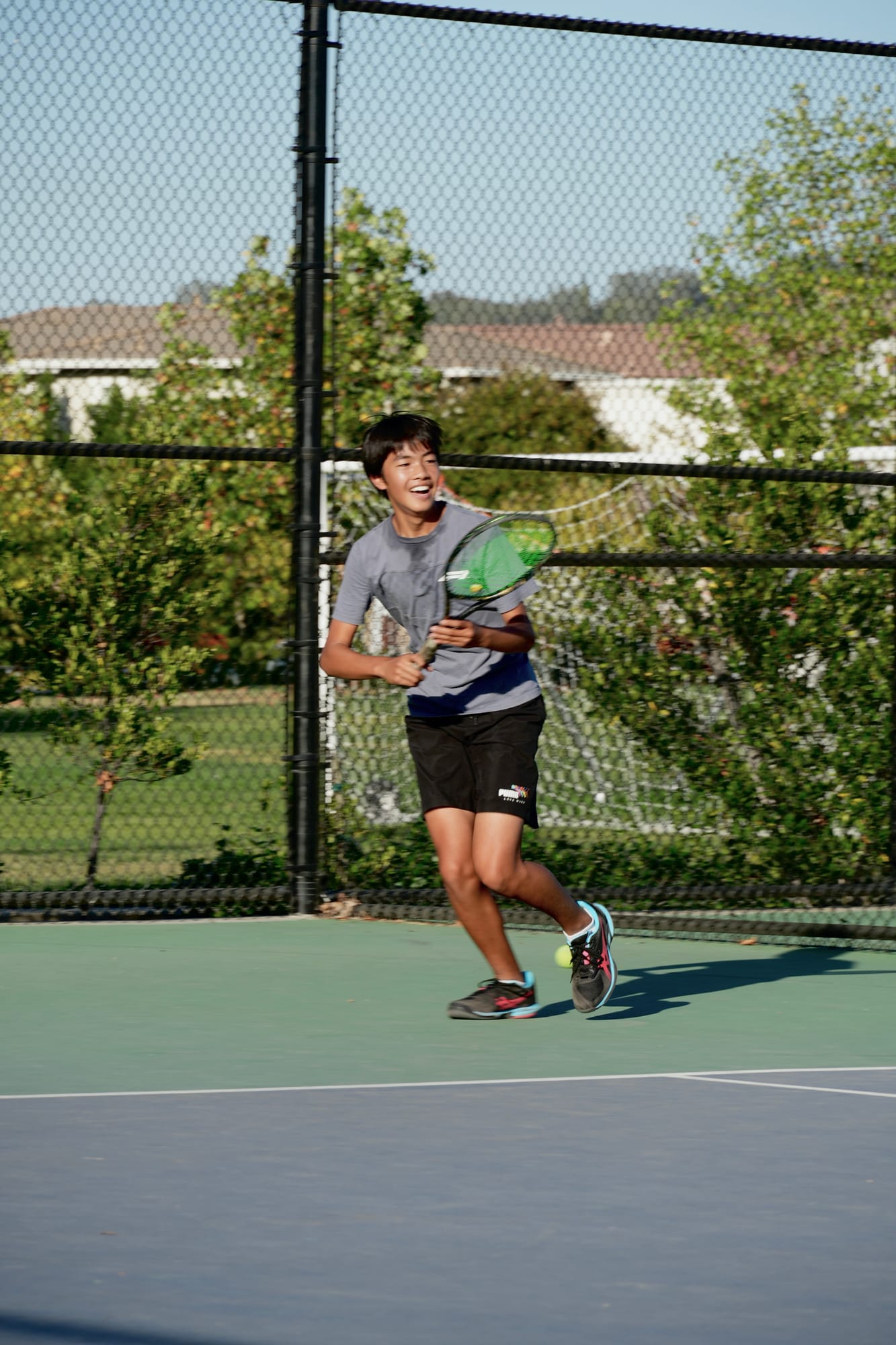 A smiling junior player running to the ball during a TNA Pro Academy session in California